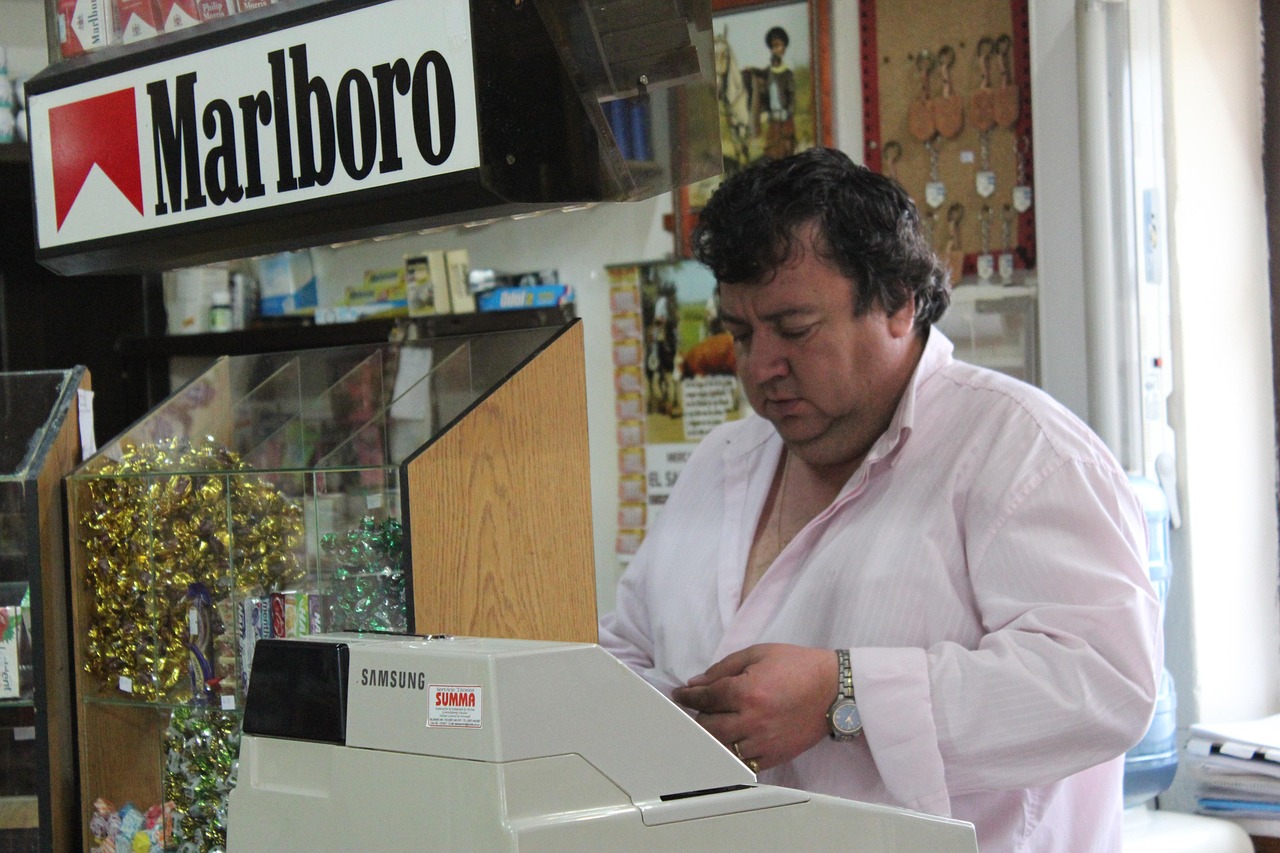 Immagine di un tabaccaio che mostra gratta e vinci con un sorriso soddisfatto.