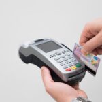 Immagine di un POS mobile utilizzato su un mezzo pubblico, evidenziando i rischi di truffe nei pagamenti contactless.